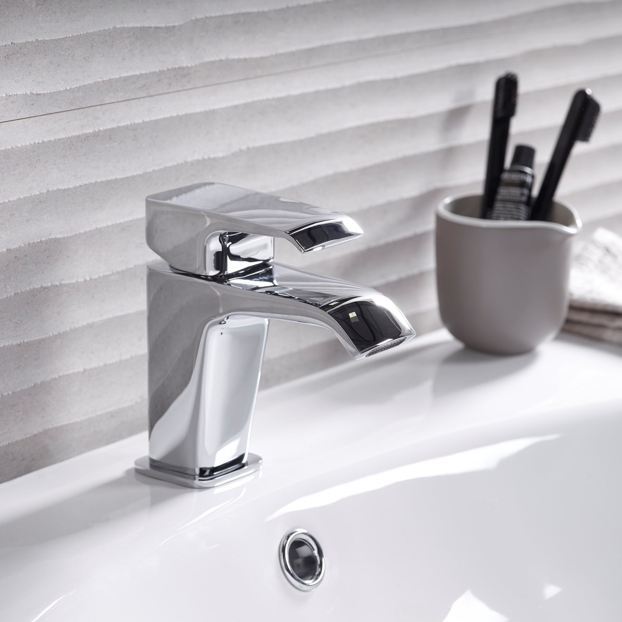 Tavistock Adapt Basin Mixer With Click Waste - Chrome  next to a tooth brush hold in front of tiles TAD11