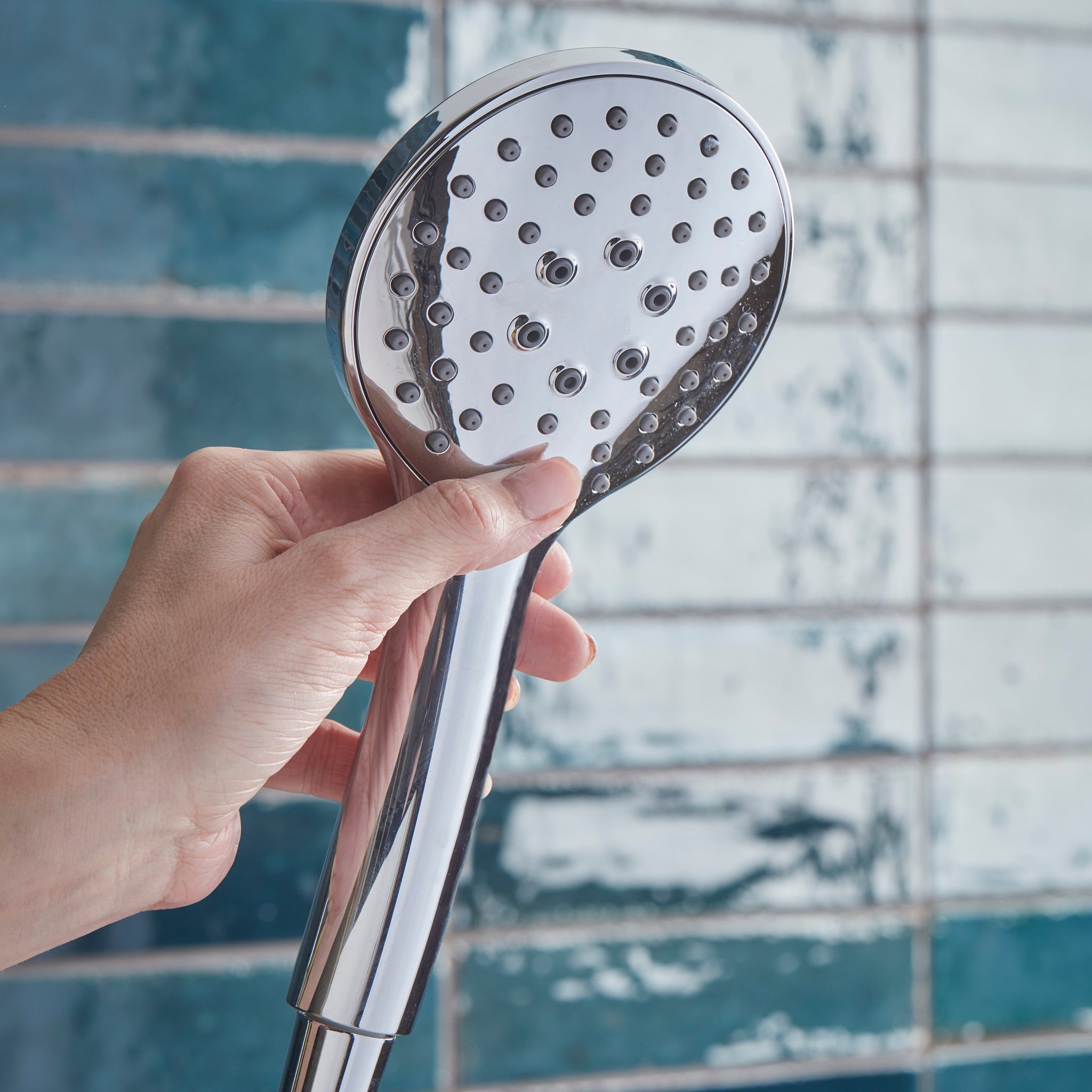 Tavistock Axiom Dual Function Push Button Shower System With Head And Outlet up close shower head against blue tiling SAX2549