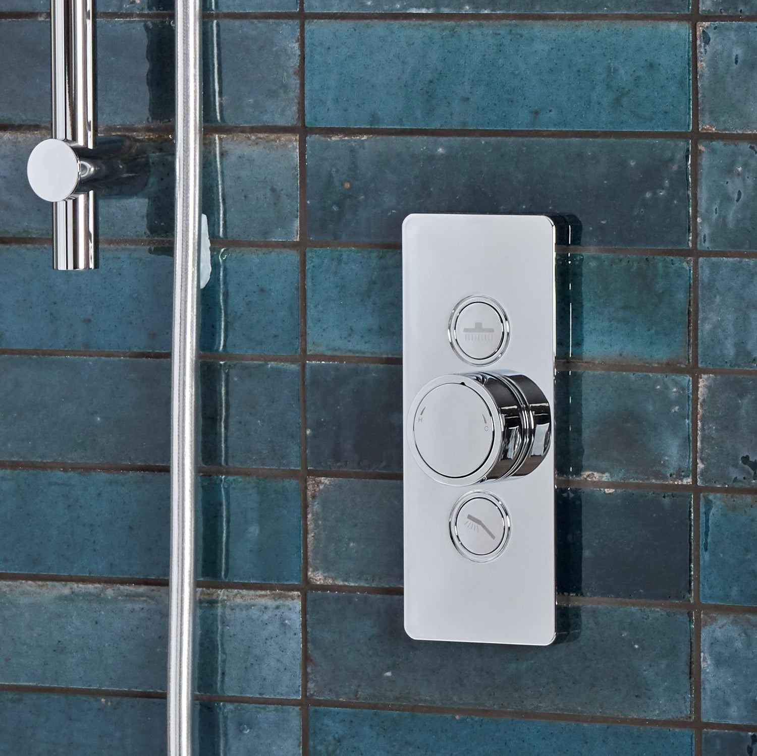 Tavistock Axiom Dual Function Push Button Shower System With Head And Riser Kit close up of controls against blue tiling SAX2516