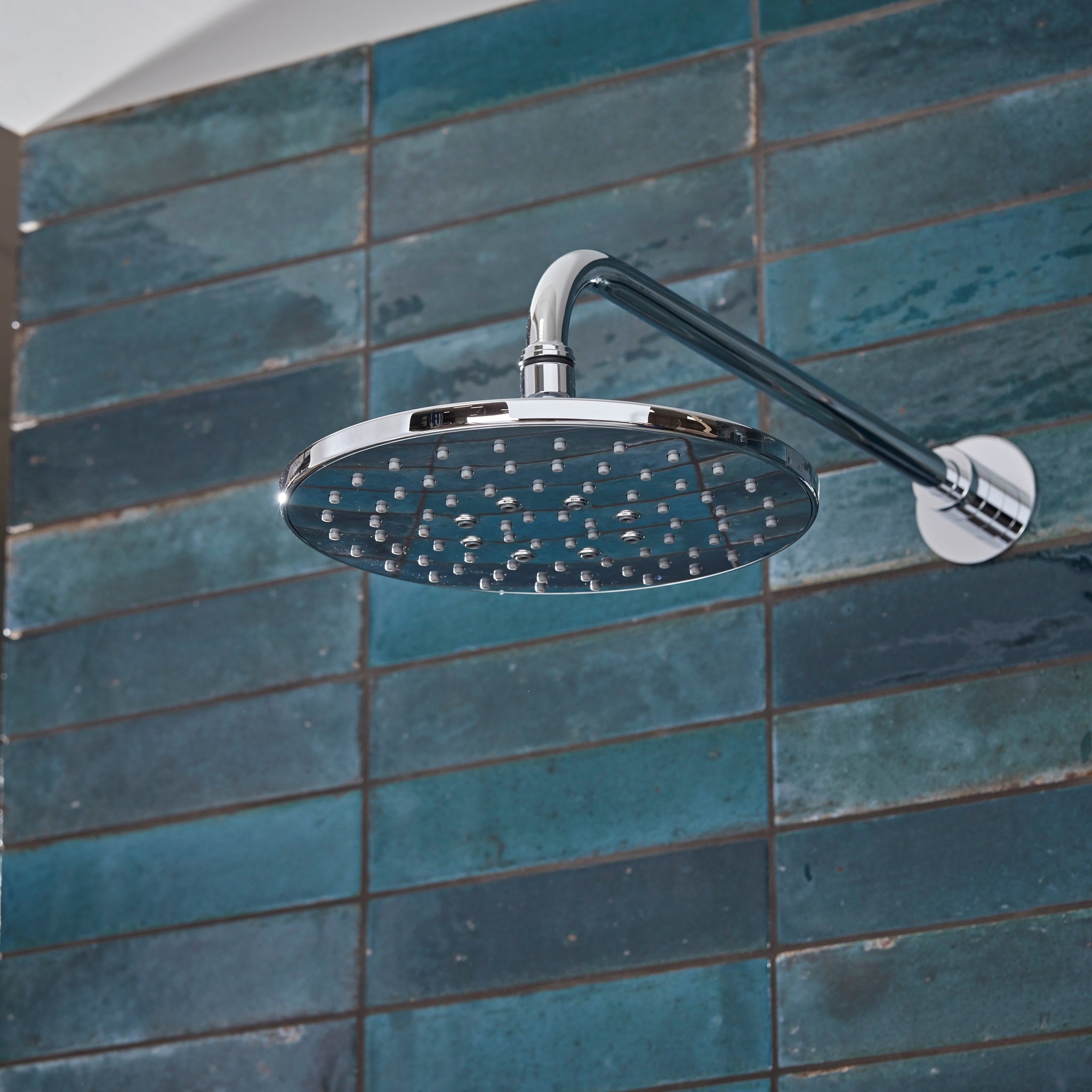 Tavistock Axiom Dual Function Push Button Shower System With Head And Outlet up close shower head against blue tiling SAX2549