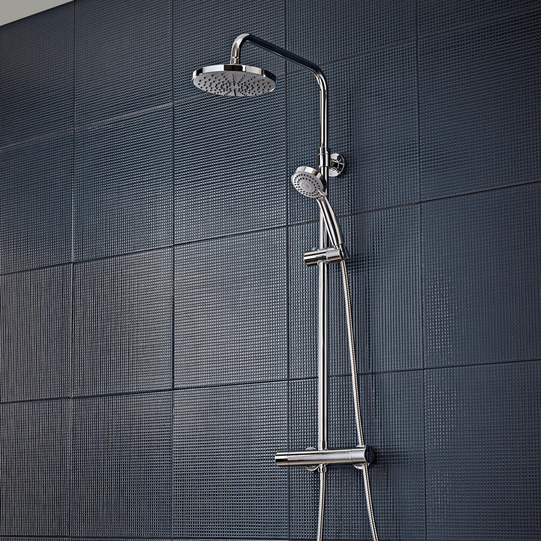Tavistock Merit Round Exposed Bar Shower System with Fixed Head and Handset against dark blue tiled wall SMT1509