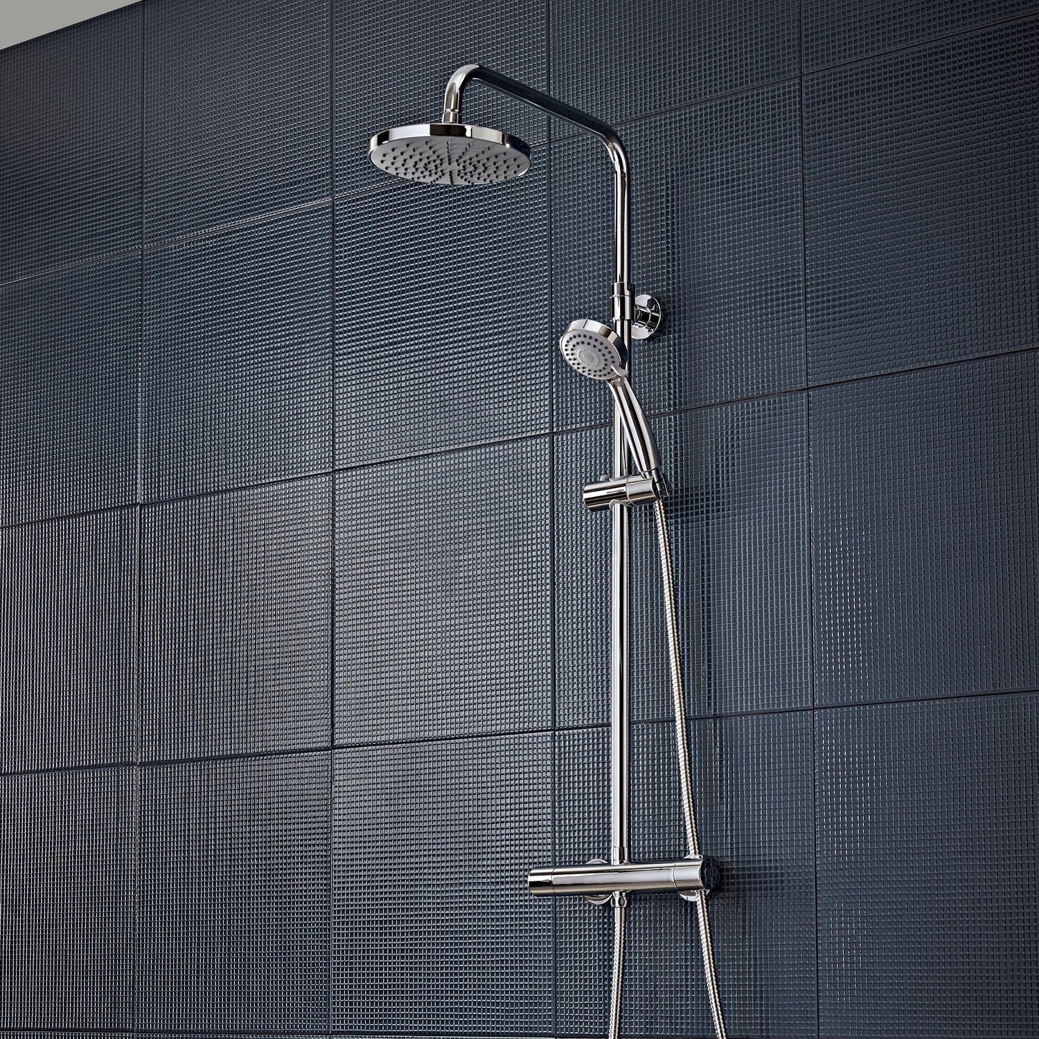 Tavistock Merit Round Exposed Bar Shower System with Fixed Head and Handset against dark blue tiled wall SMT1509