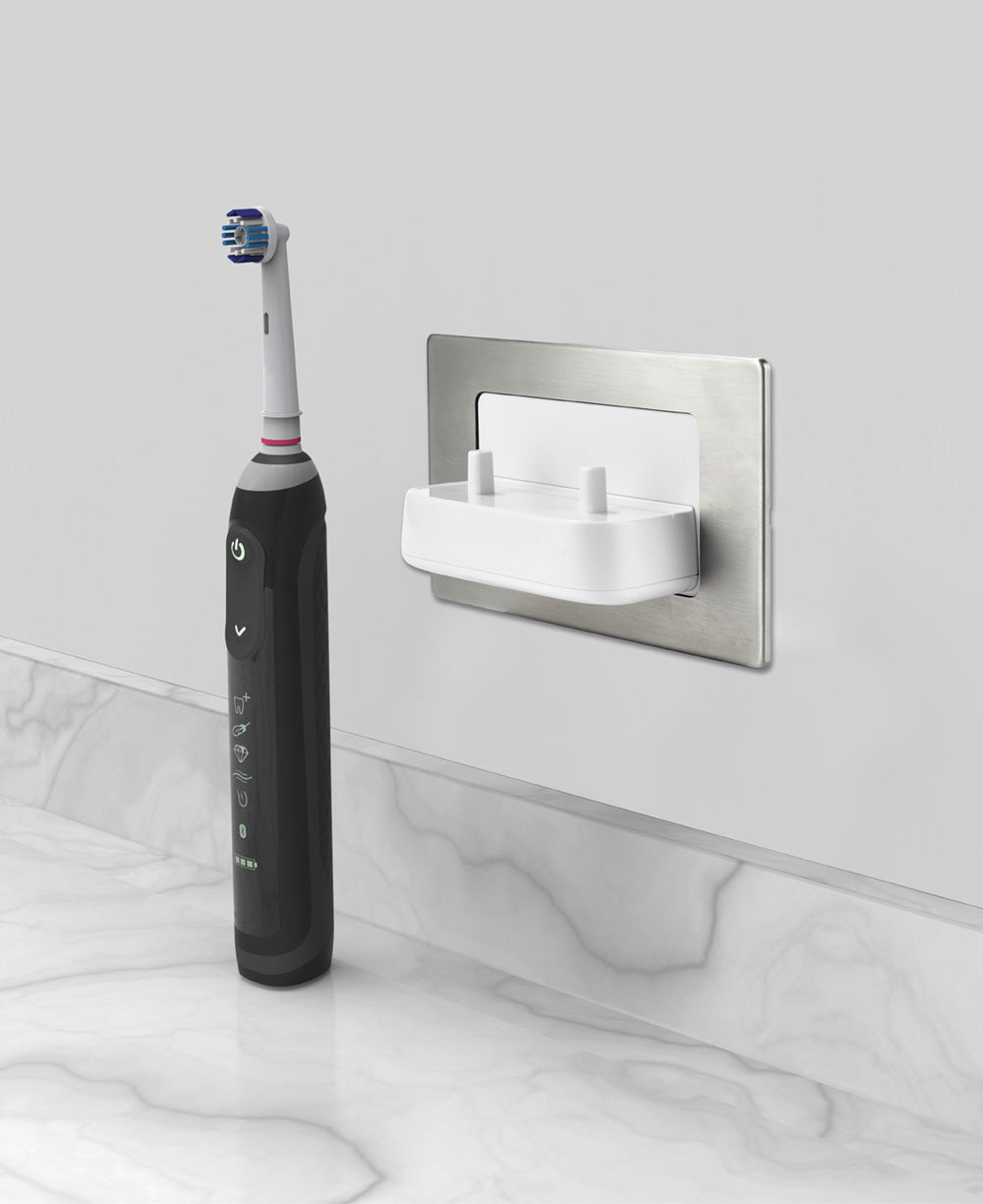 ProofVision In-Wall Dual Electric Toothbrush Charger tooth brush next to the charger on counter top in grey PV11P
