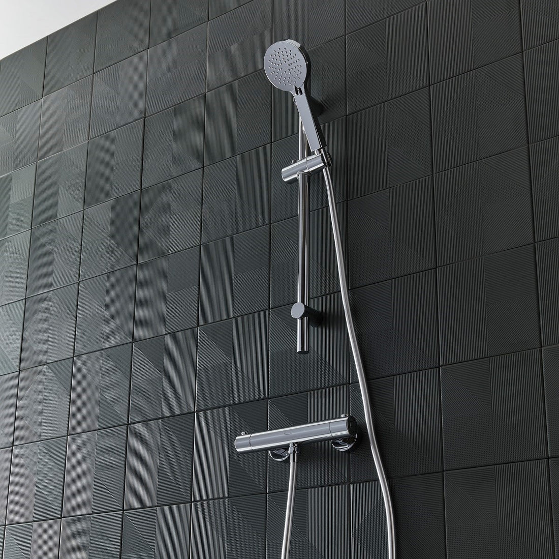 Tavistock Quantum Exposed Cool Touch Outlet Shower System with Slide Rail Kit against a tiled design in grey SQT2416