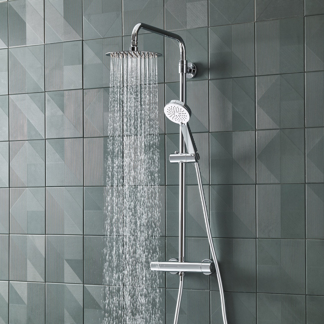 Tavistock Quantum Exposed Cool Touch Outlet Shower System with Fixed Head and Handset against light grey tiles SQT2209