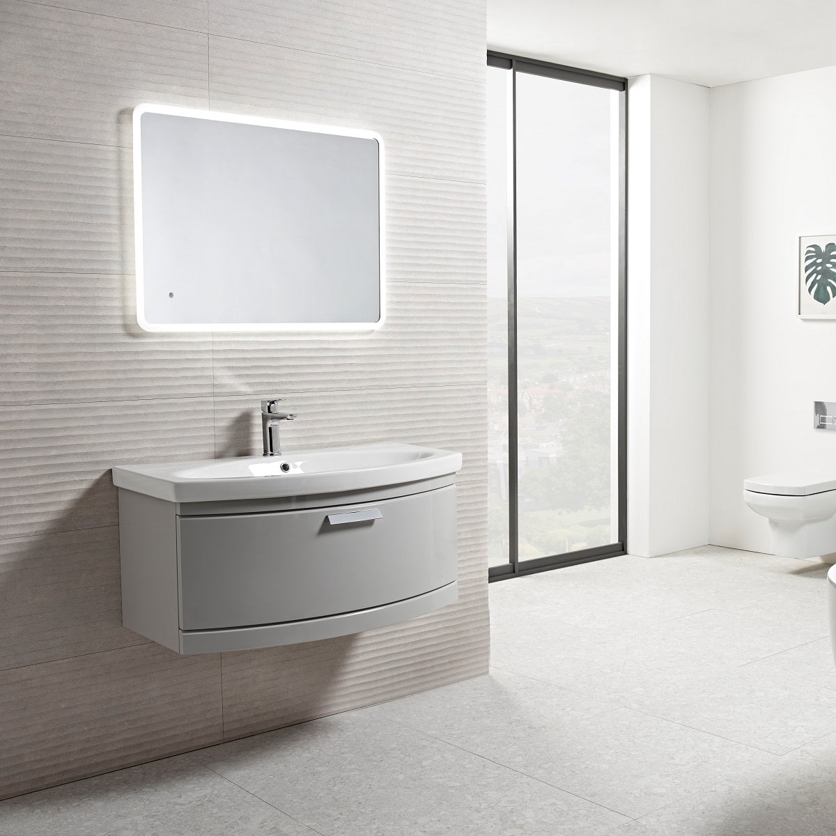 Tavistock Tempo 900mm Wall Mounted Unit &amp; Basin - Various Colours wide view showing the unit against a stone wall design underneath a light up mirror  TE900WG